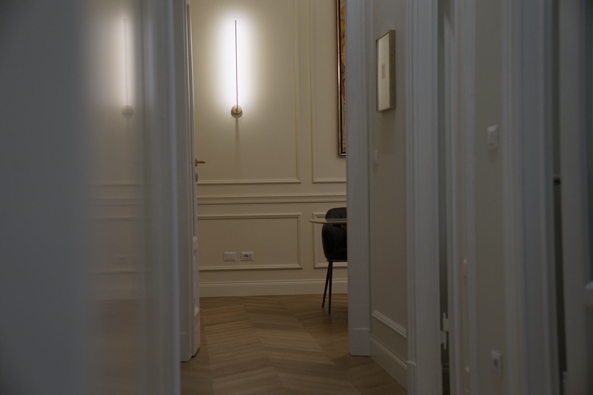 Vista da soglia · applique verticale, quadro figurativo, poltrona scura · sala riunioni piccola