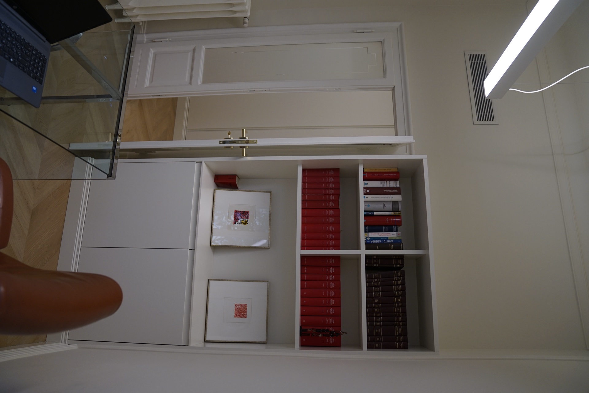 Ufficio biblioteca con libreria di codici giuridici e scrivania in vetro