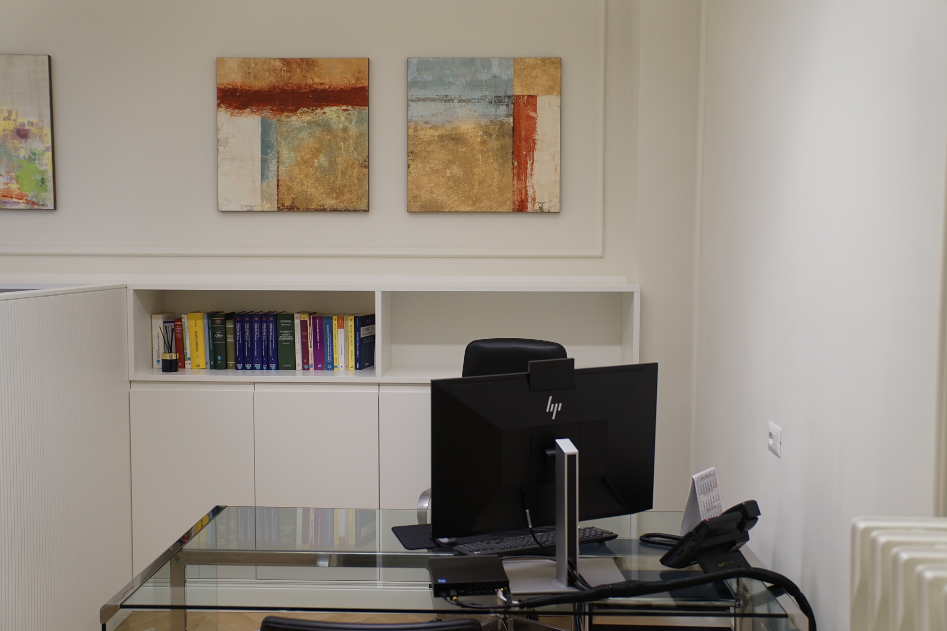 Ufficio interno con scrivania in vetro · dittico di quadri astratti texture e codici giuridici