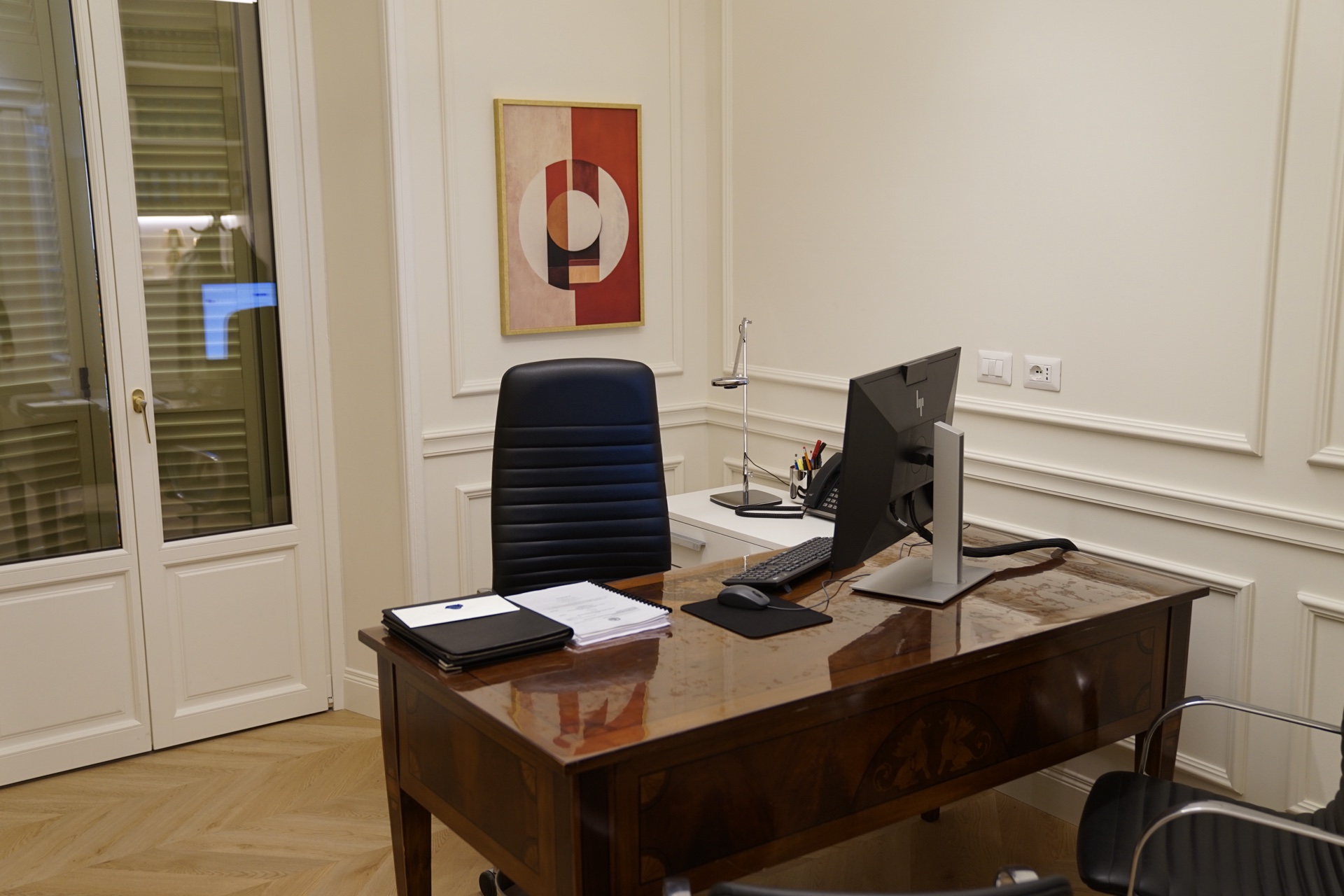 Ufficio con scrivania in legno · sedia in pelle blu, monitor e quadro astratto