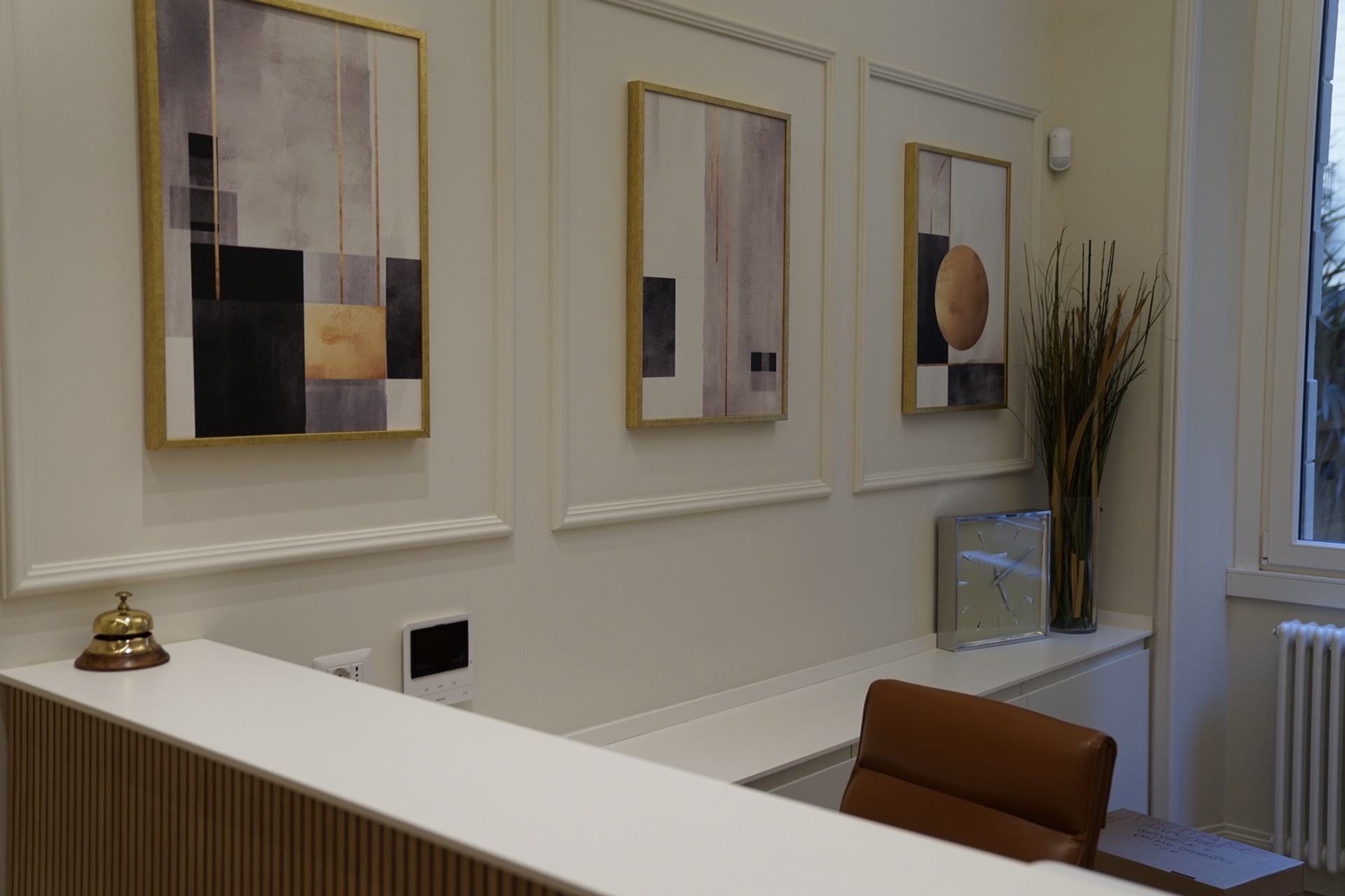 Reception · tre quadri astratti con cornici dorate, clock di vetro